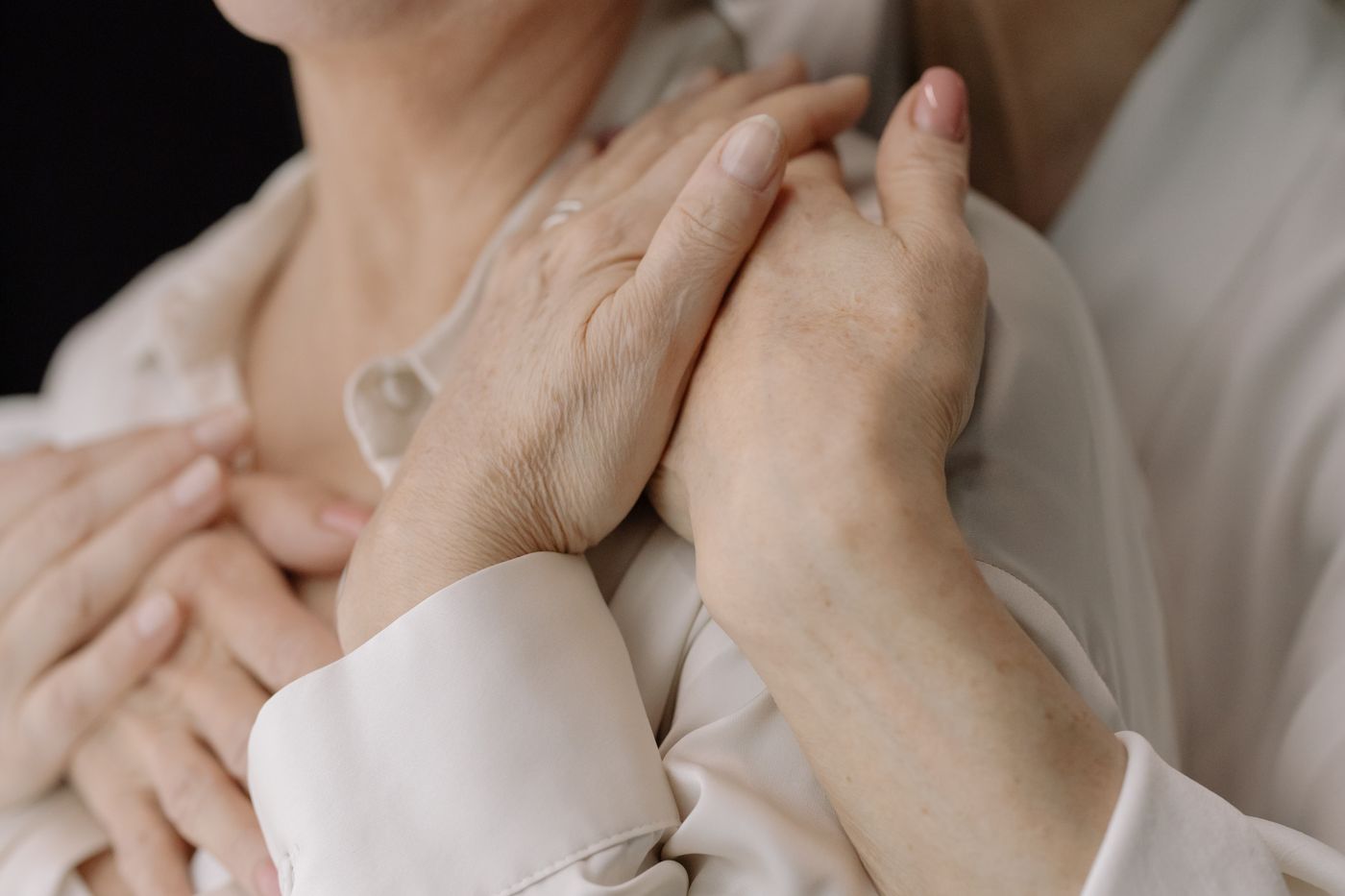 A caregiver gently holding the hands of an elderly patient